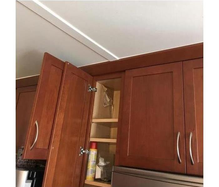 Water damage above brown cabinets in kitchen of home.