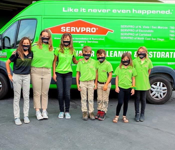 Kids gathered in front of green truck in green SERVPRO shirts.
