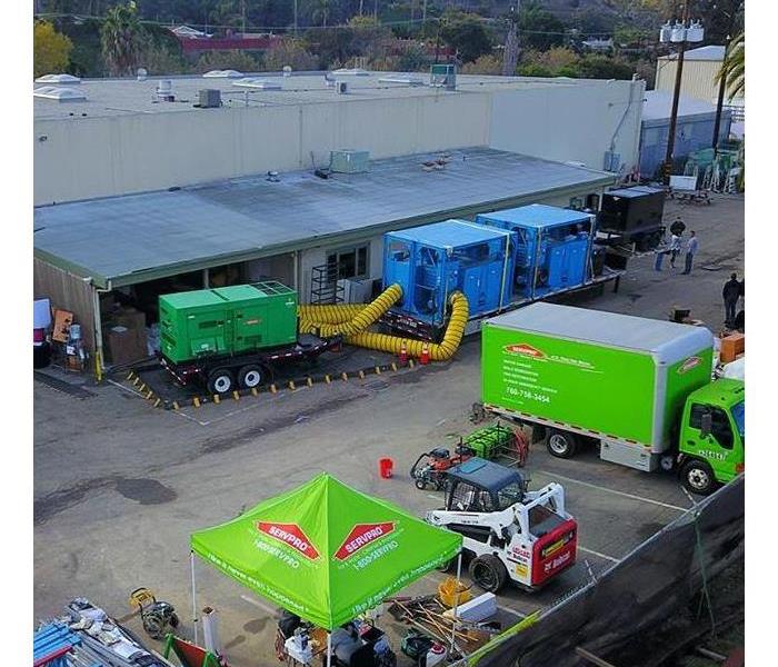 Green trucks and contents set up at a school parking lot.