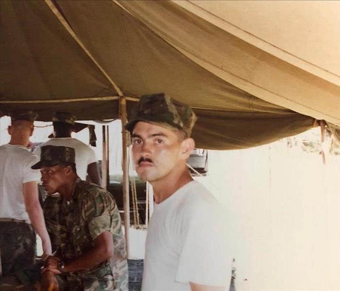 A man in military uniform under a tent.